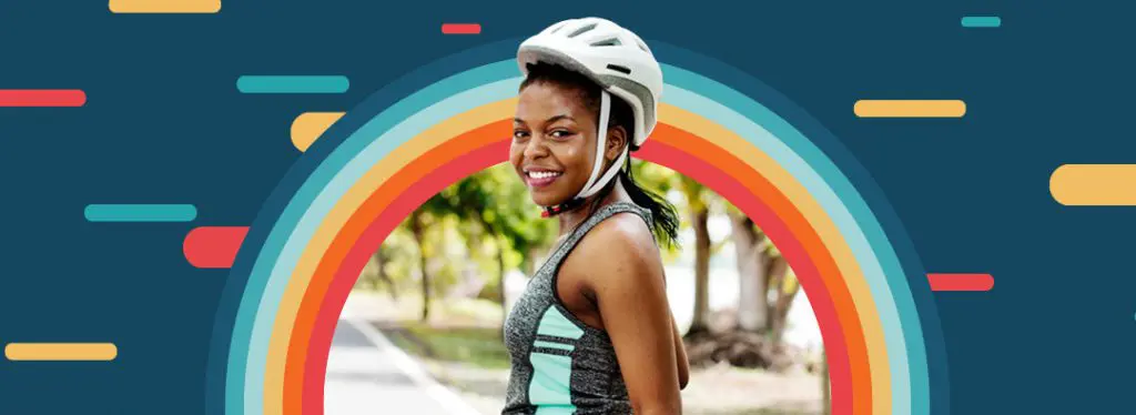 Image a person smiling wearing a bike helmet with bold multi color graphics behind them