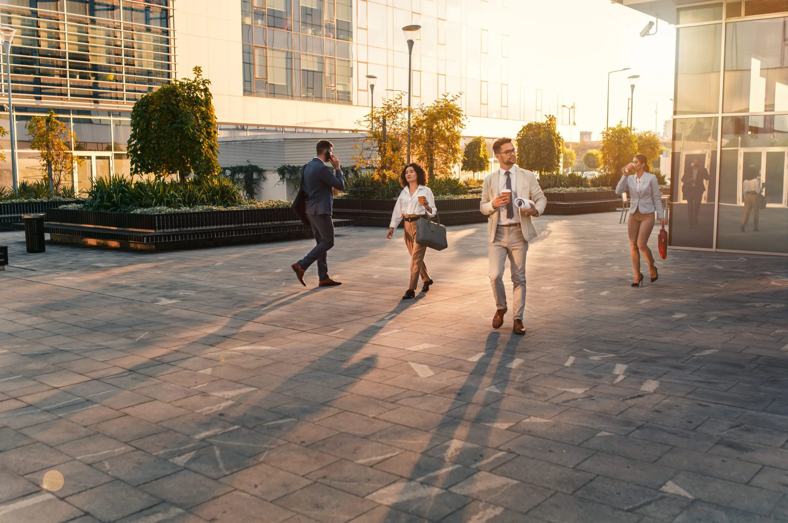 Group of professionally dressed men and women walking outside in front of an office.