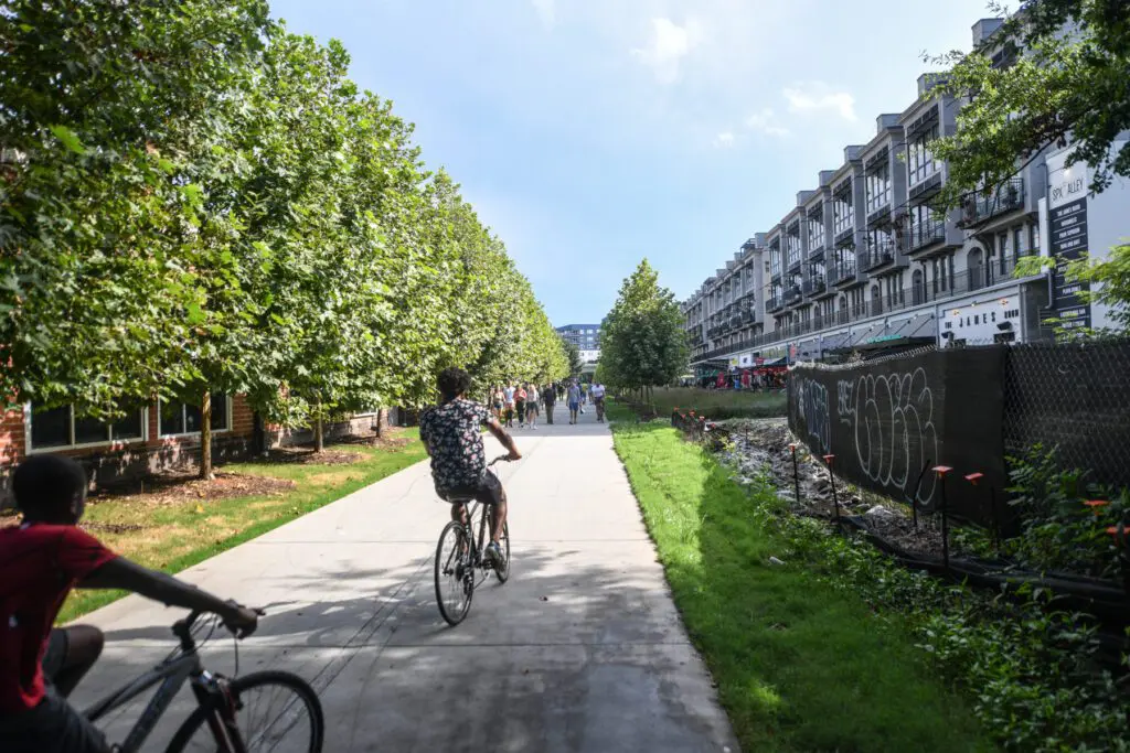 View of atlanta walk way where multiple people are walking and two people are riding bikes.