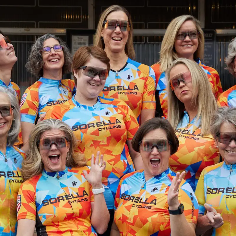 Cyclists from Sorella Cycling, an all-womens cycling club in Atlanta pose for a photo wearing their brightly-colored cycling gear.