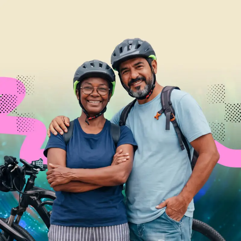 Two adults wearing helmets stand close together, smiling beside bicycles. The background is a digital mix of abstract patterns with pink and black shapes on a light and blue gradient backdrop.