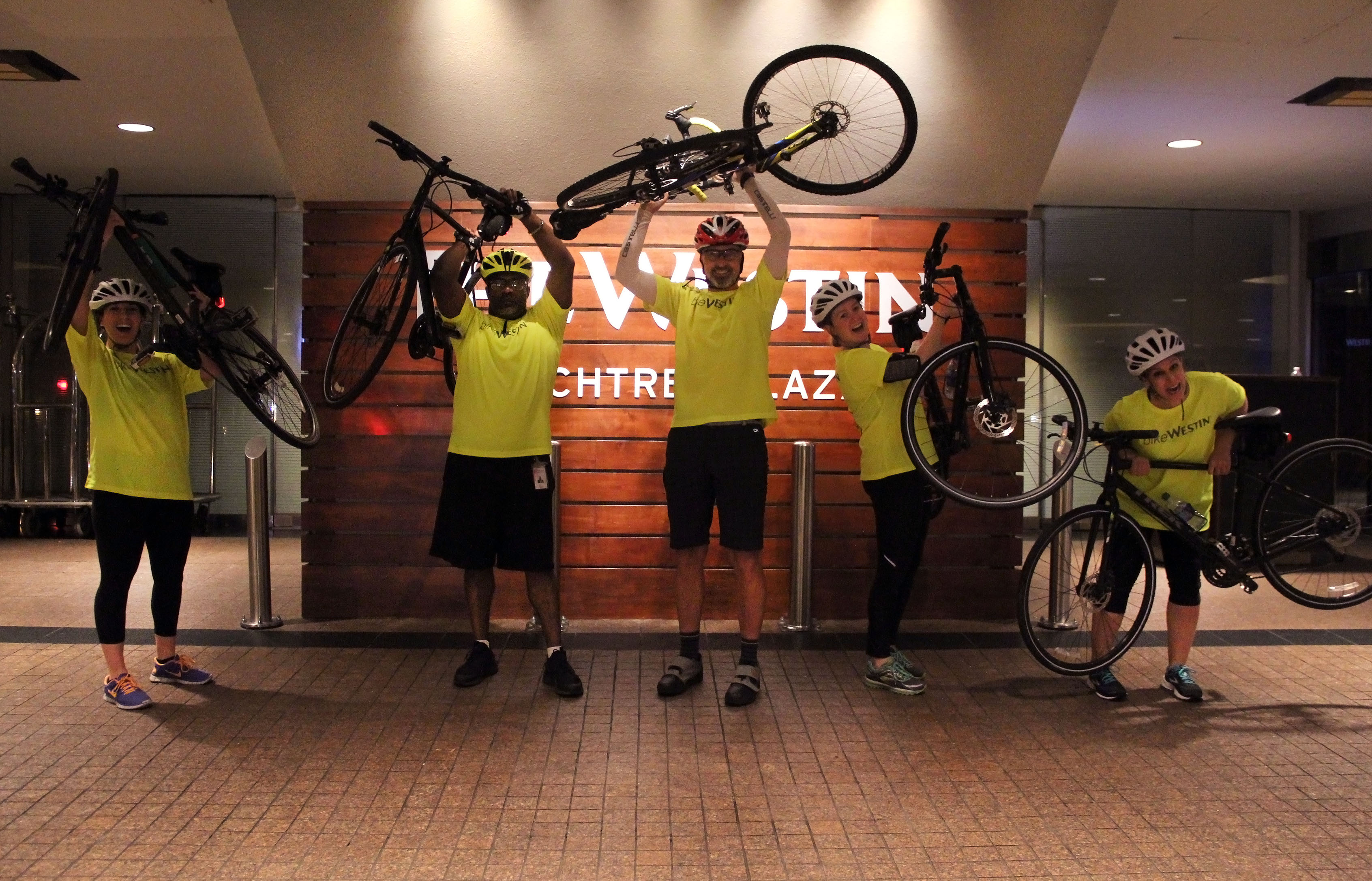 Image of 5 people holding up bikes in celebration