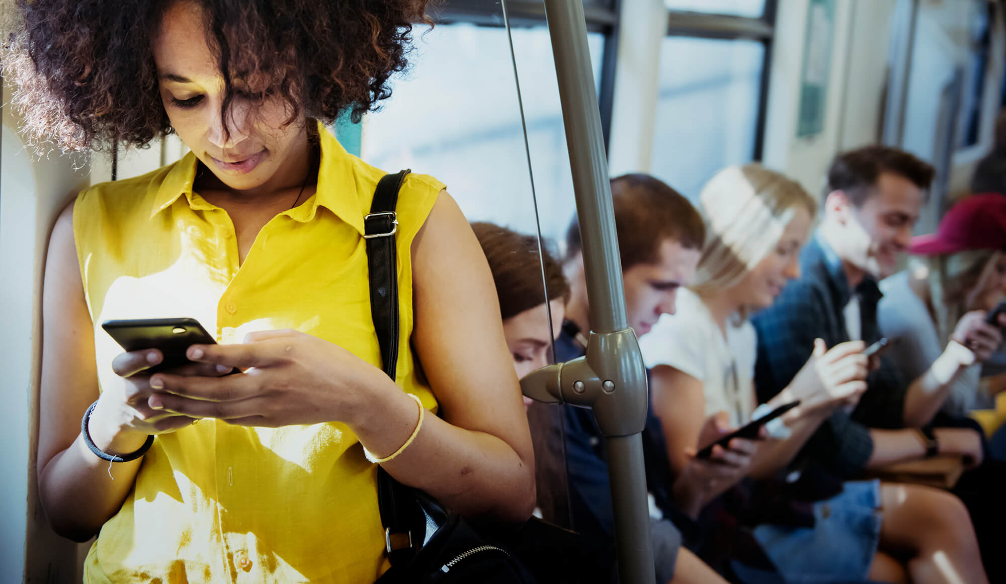 Five commuters are on a bus on their smartphones.