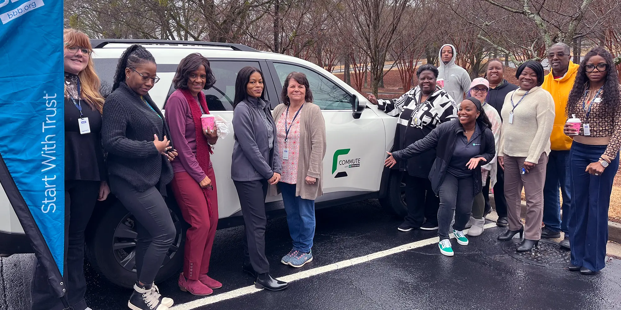 A group of people taking a photo in front of a car.