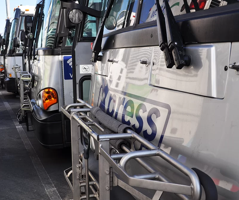 A fleet of Xpress buses are parked in a lot.