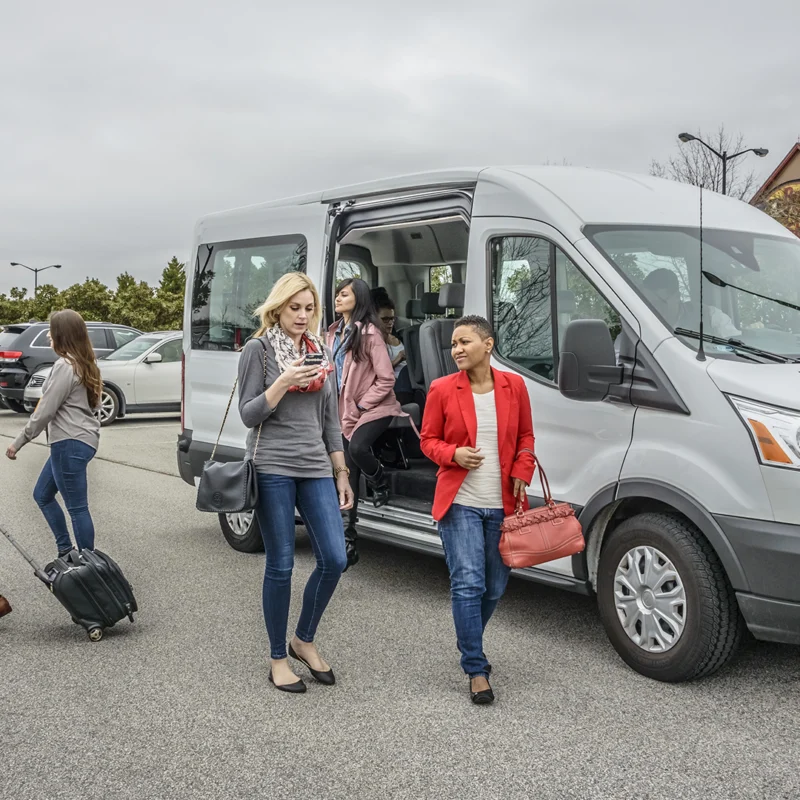 Five passengers are walking away from their vanpool. The driver and one passenger are still onboard.