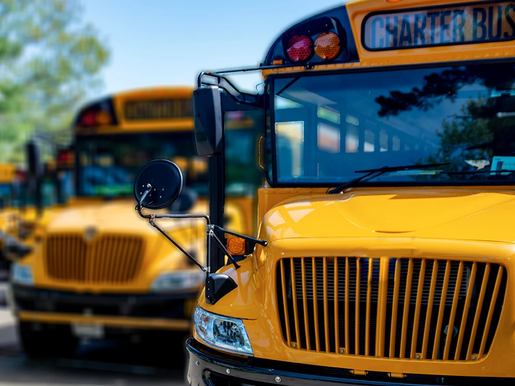 Up close of front of school bus with multiple school busses in the background.