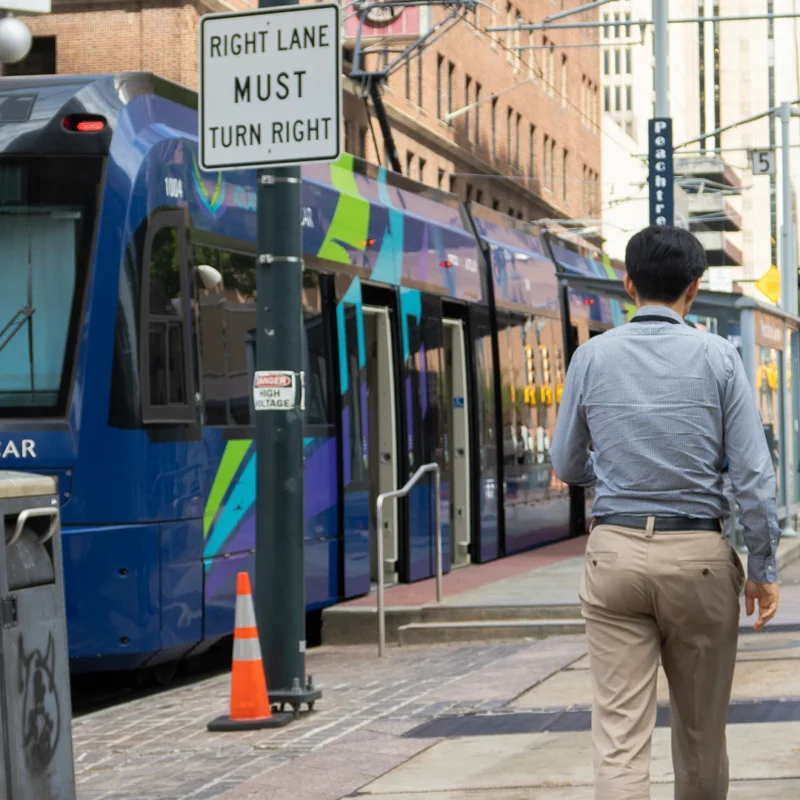 Two people are walking down a street, there is an Atlanta street car passing by them.